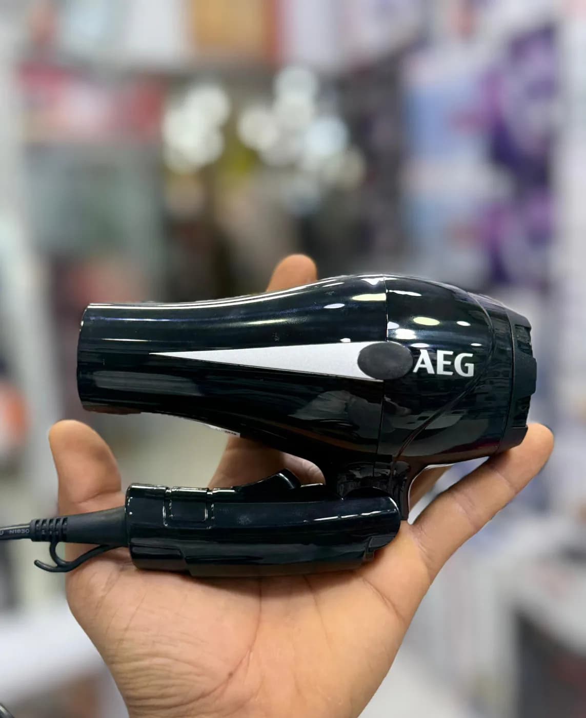 سشوار AEG AG-2038 روی کف دست؛ ابعاد کوچک و دسته تاشوی آن اندازه جمع‌وجور محصول را نشان می‌دهد