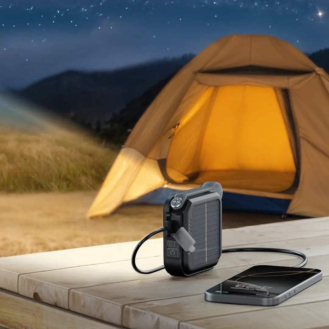 چراغ Lumix روی میز چوبی کنار چادر در شب، در حال شارژ یک گوشی با کابل از خروجی USB-A