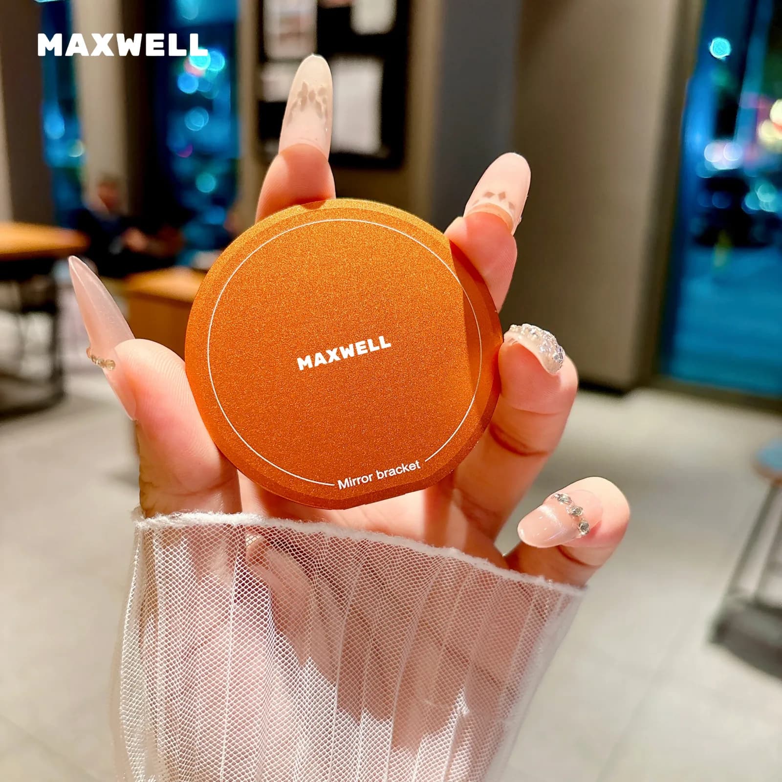 بدنه گرد و بسته رینگ هولدر مکسول با لوگوی MAXWELL و عبارت Mirror bracket، در دست