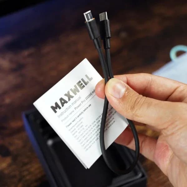 کابل شارژ داخل جعبه و دفترچه راهنمای MAXWELL با عنوان Power Pro 20000 mAh در دست