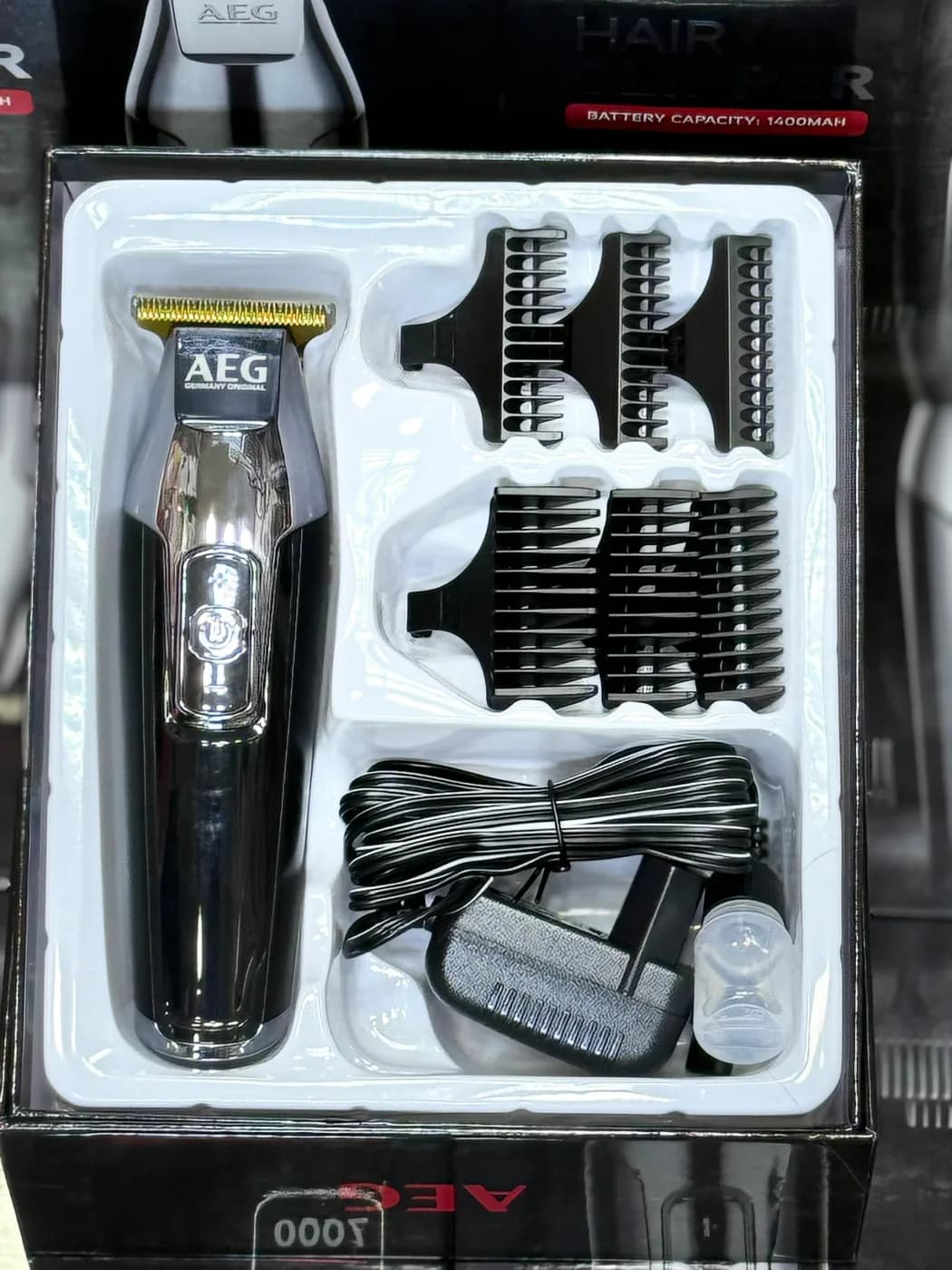 جعبه باز ماشین اصلاح AEG AG-2035 با شانههای اصلاح، کابل شارژ، برس تمیزکننده و ظرف روغن داخل سینی بستهبندی